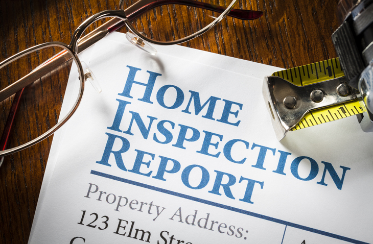 Home Inspection Report with measuring tape and glasses on desk